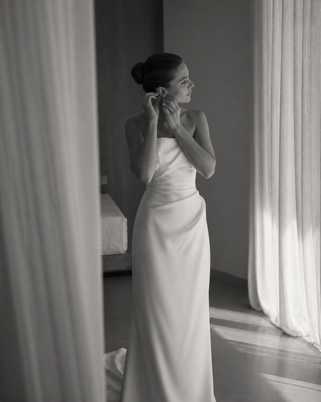 Bride adjusting an earring in soft window light