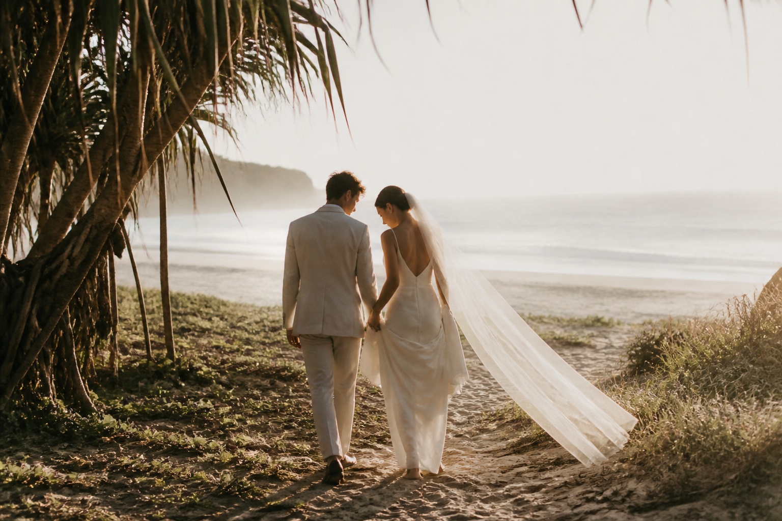 Newlyweds walking from coastal shade towards the sea