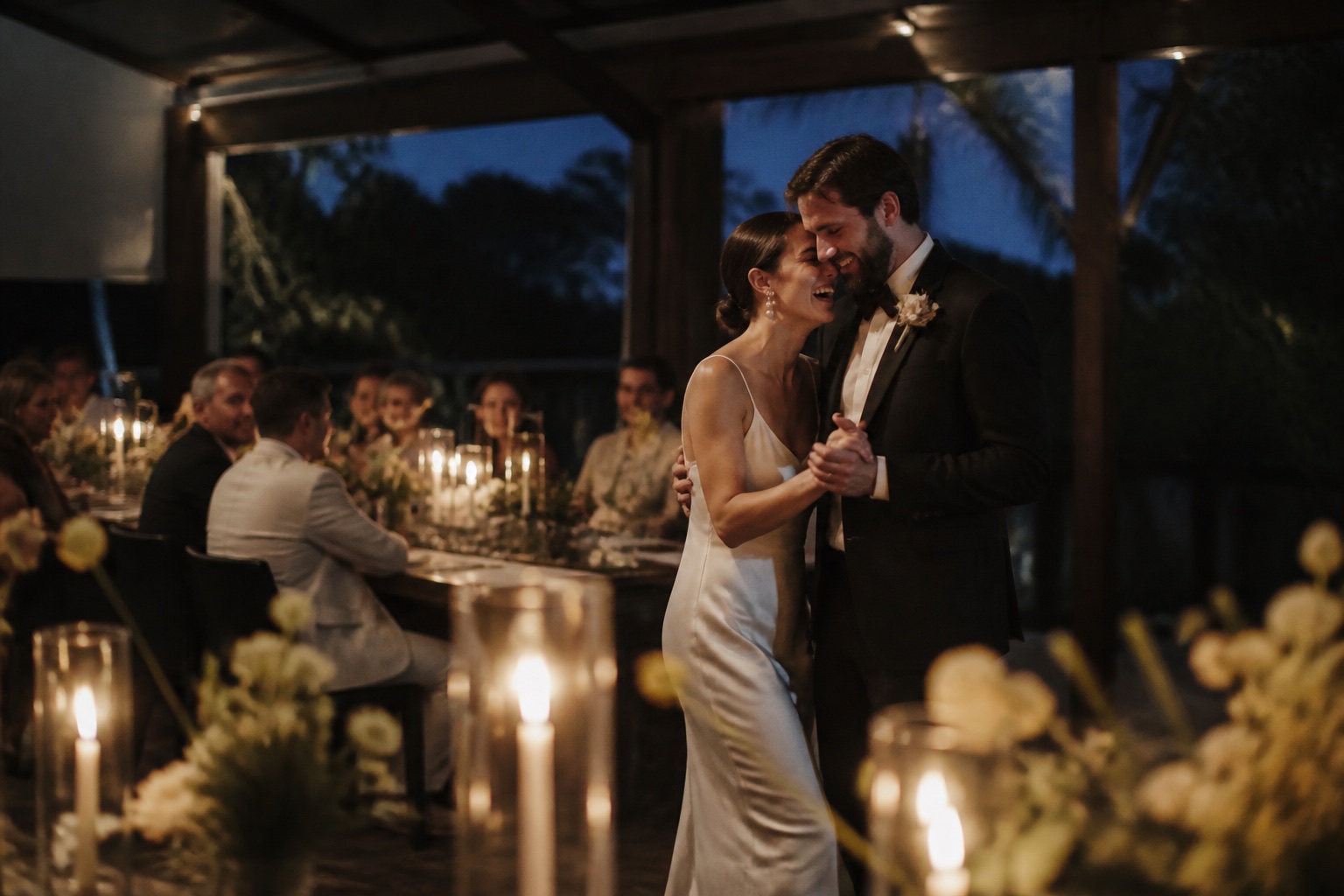 Newlyweds laughing together during their candlelit first dance
